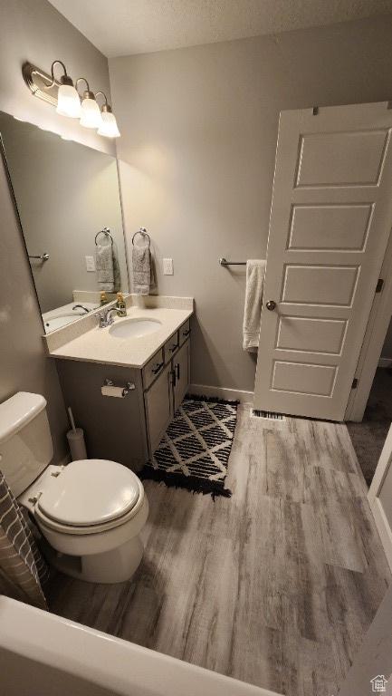 1395 E Kelsey Dr, Eagle Mountain, UT 84005 - bathroom featuring baseboards, wood finished floors, toilet, and vanity