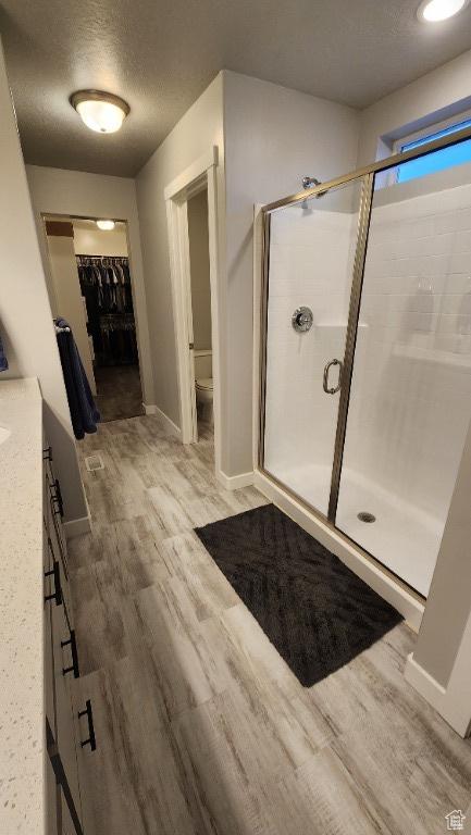 1395 E Kelsey Dr, Eagle Mountain, UT 84005 - full bath with a textured ceiling, wood finished floors, toilet, and a shower stall
