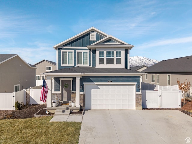 view of front facade featuring board and batten siding, concrete driveway, fence, and a gate