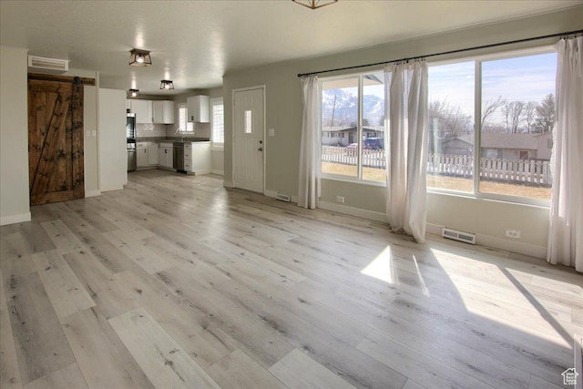 454 E 3100 N, North Ogden, UT 84414 - unfurnished living room with a barn door, plenty of natural light, light wood-style floors, and visible vents