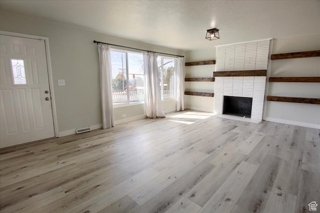 454 E 3100 N, North Ogden, UT 84414 - unfurnished living room featuring light wood-type flooring, baseboards, a brick fireplace, and visible vents