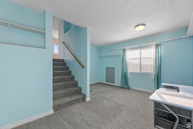 interior space with carpet flooring, a textured ceiling, and baseboards