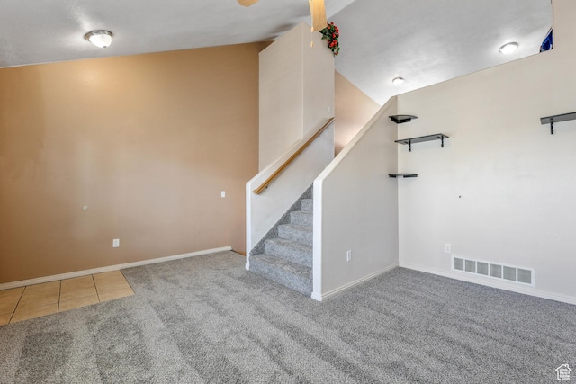 basement featuring carpet, visible vents, baseboards, tile patterned flooring, and stairs