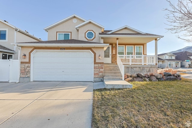 view of front facade featuring stone siding, covered porch, concrete driveway, and stucco siding