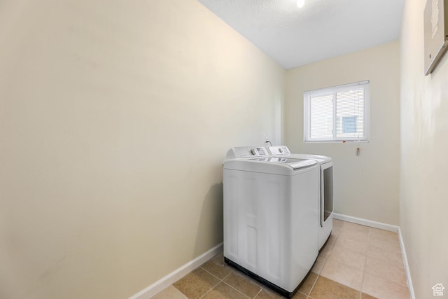laundry area featuring laundry area, light tile patterned floors, washing machine and dryer, and baseboards