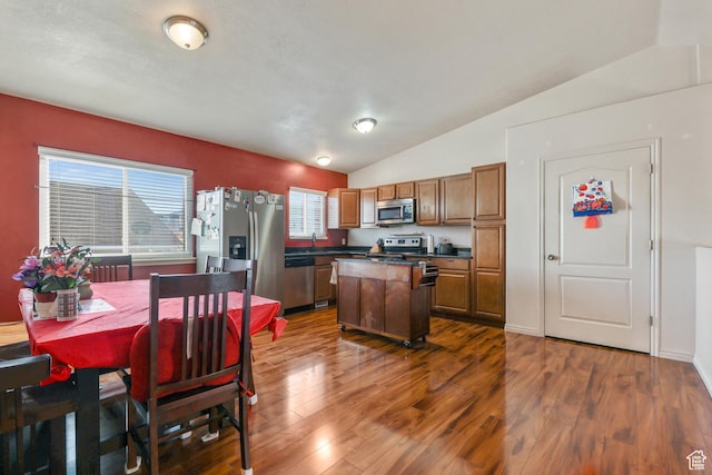 kitchen with dark countertops, appliances with stainless steel finishes, dark wood-style floors, and a center island