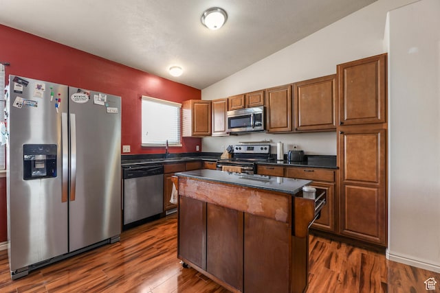 kitchen featuring lofted ceiling, dark countertops, appliances with stainless steel finishes, and dark wood-style flooring