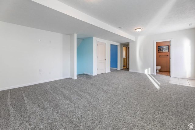 carpeted empty room with a textured ceiling and baseboards
