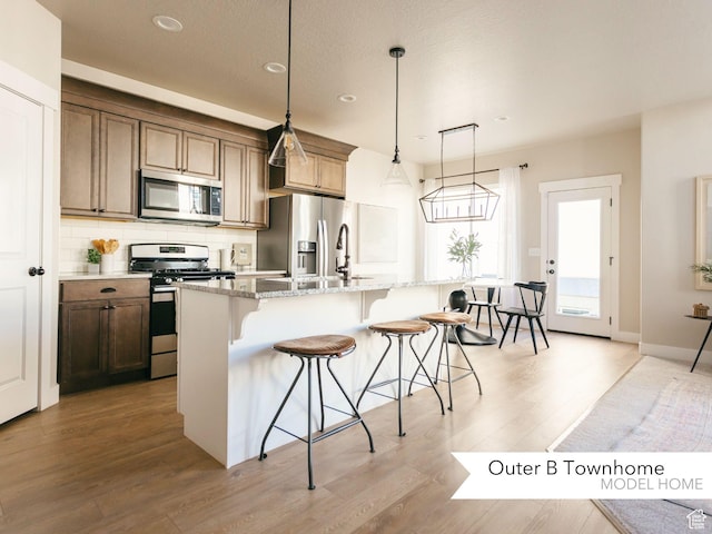 kitchen with a breakfast bar area, recessed lighting, light wood-style floors, and appliances with stainless steel finishes