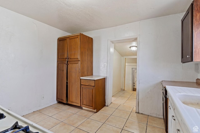 171 17th St, Ogden, UT 84404 - kitchen featuring light countertops, brown cabinets, light tile patterned floors, and a sink