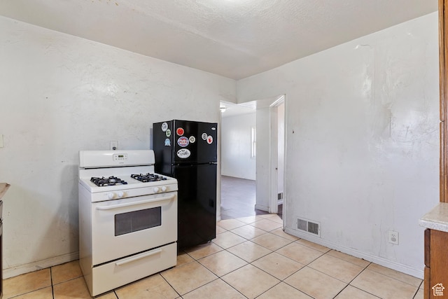 171 17th St, Ogden, UT 84404 - kitchen featuring white gas range, freestanding refrigerator, light tile patterned floors, light countertops, and baseboards