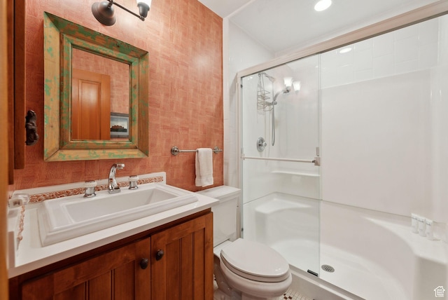 full bath with a stall shower, toilet, and vanity