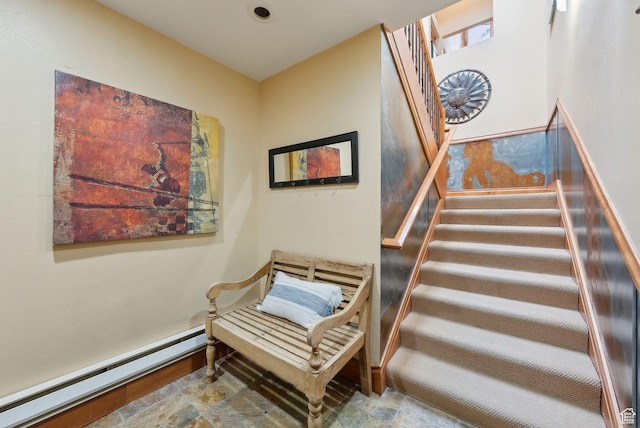 staircase featuring stone finish floor, a baseboard heating unit, and baseboards