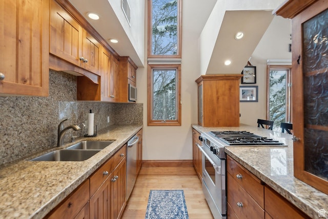 kitchen featuring visible vents, a sink, light wood-style floors, appliances with stainless steel finishes, and brown cabinetry