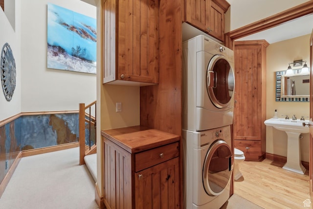 clothes washing area featuring laundry area, stacked washer / dryer, and light wood-type flooring