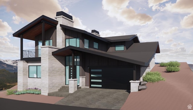 contemporary home with a balcony, an attached garage, a chimney, stone siding, and aphalt driveway