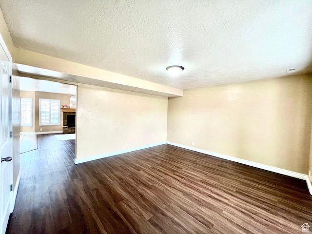 15 E 1100 S, Vernal, UT 84078 - spare room with visible vents, a fireplace with raised hearth, a textured ceiling, dark wood-style floors, and baseboards