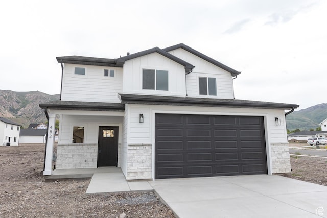1183 S 1335 E Unit 76, Garland, UT 84312 - view of front facade featuring an attached garage, board and batten siding, concrete driveway, covered porch, and a mountain view