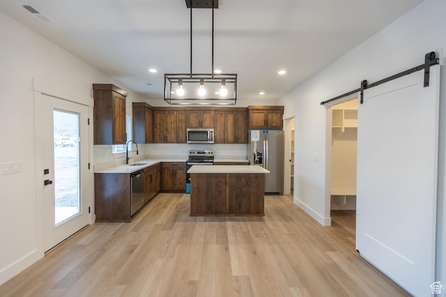 1183 S 1335 E Unit 76, Garland, UT 84312 - kitchen featuring light countertops, a barn door, light wood-style flooring, appliances with stainless steel finishes, and a sink