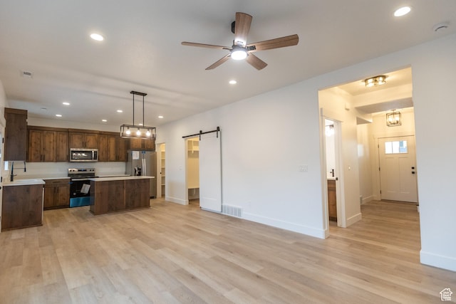 1183 S 1335 E Unit 76, Garland, UT 84312 - kitchen featuring visible vents, a kitchen island, appliances with stainless steel finishes, a barn door, and open floor plan