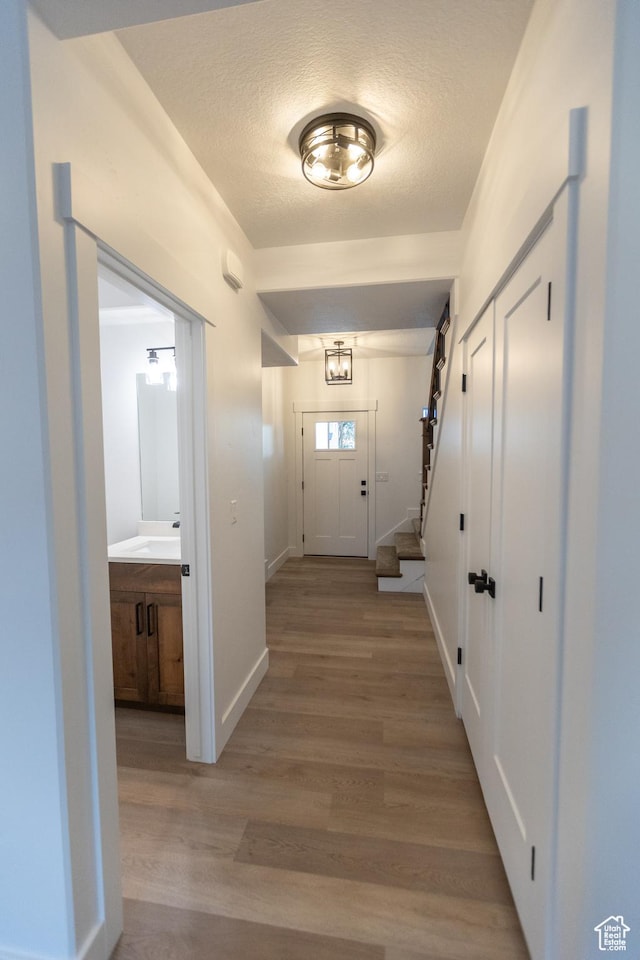 1183 S 1335 E Unit 76, Garland, UT 84312 - doorway featuring stairs, light wood-style flooring, baseboards, and a textured ceiling