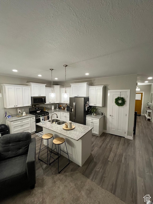 kitchen featuring dark wood finished floors, recessed lighting, a sink, appliances with stainless steel finishes, and white cabinetry