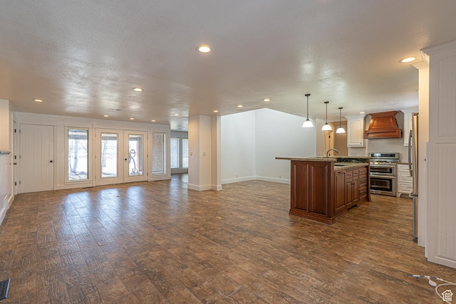 717 E Park Dr N, Hyrum, UT 84319 - kitchen featuring dark wood finished floors, custom exhaust hood, an island with sink, appliances with stainless steel finishes, and open floor plan