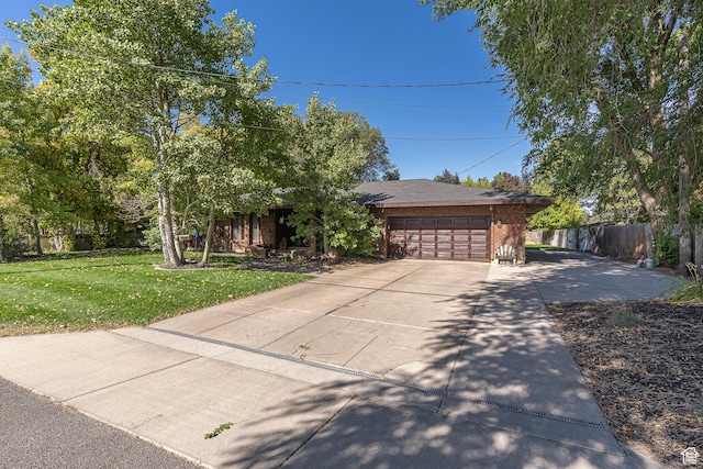 view of front facade with driveway, a front lawn, fence, a garage, and brick siding