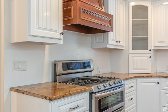 717 E Park Dr N, Hyrum, UT 84319 - kitchen with range with two ovens, glass insert cabinets, white cabinets, and custom range hood