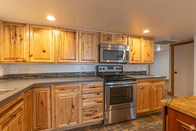 717 E Park Dr N, Hyrum, UT 84319 - kitchen featuring dark countertops, visible vents, a textured ceiling, and appliances with stainless steel finishes