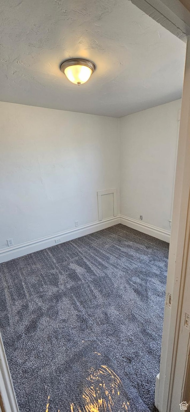 279 E 2nd St N, Downey, ID 83234 - empty room featuring dark colored carpet, baseboards, and a textured ceiling