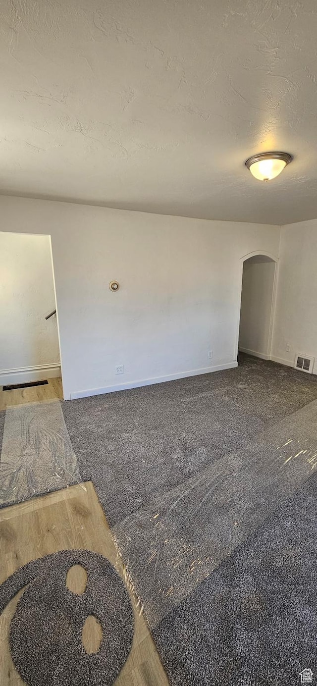 279 E 2nd St N, Downey, ID 83234 - empty room featuring visible vents, baseboards, carpet flooring, arched walkways, and a textured ceiling