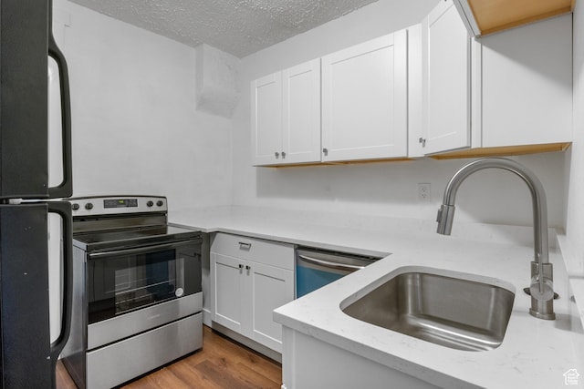 739 24th St, Ogden, UT 84401 - kitchen featuring wood finished floors, a sink, stainless steel appliances, a textured ceiling, and white cabinetry