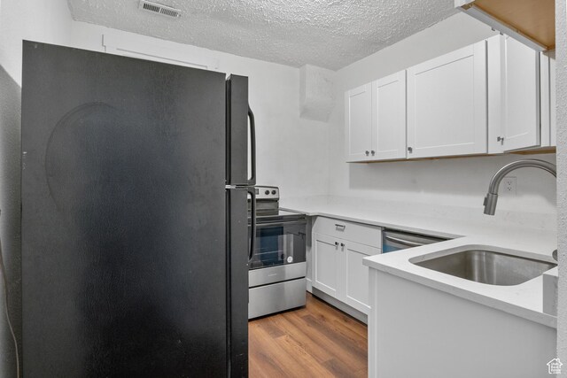 739 24th St, Ogden, UT 84401 - kitchen with wood finished floors, visible vents, freestanding refrigerator, a sink, and stainless steel range with electric cooktop