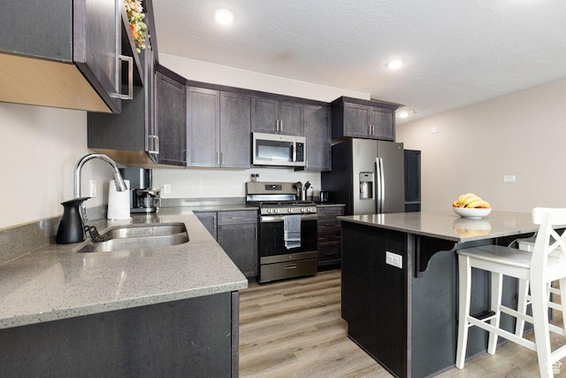 3180 W 1650 N Unit B, Cedar City, UT 84721 - kitchen with a breakfast bar, a sink, stainless steel appliances, a textured ceiling, and light wood-type flooring