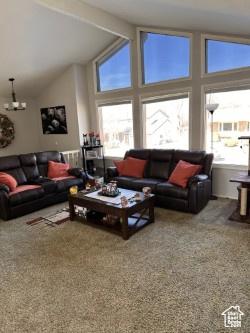 living room featuring beam ceiling, a chandelier, carpet floors, and high vaulted ceiling