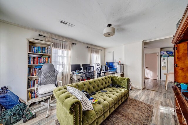 living room with visible vents, light wood-style floors, and ornamental molding