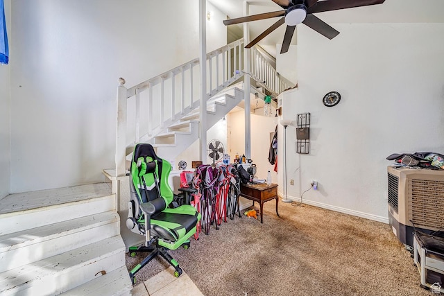 stairs with carpet flooring, ceiling fan, a high ceiling, and baseboards