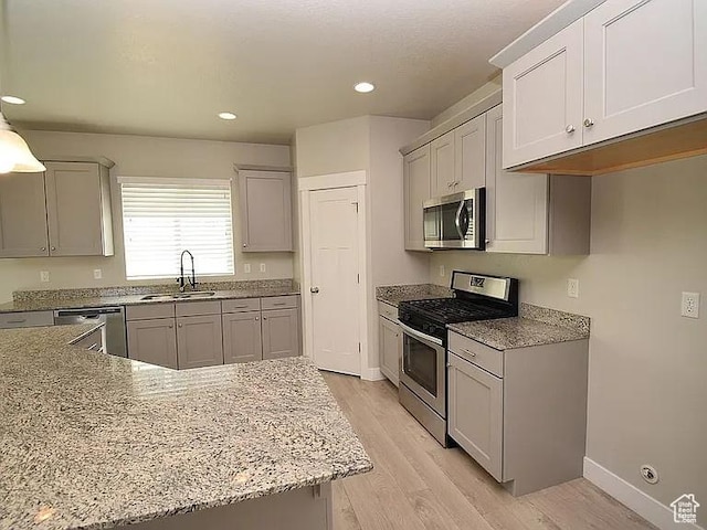 4929 W Red Ruby Ln, Herriman, UT 84096 - kitchen with appliances with stainless steel finishes, light stone countertops, a sink, recessed lighting, and light wood-style flooring
