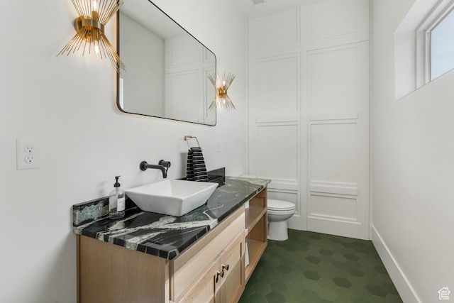 bathroom featuring baseboards, toilet, and vanity