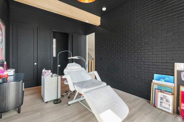 bedroom featuring brick wall and light wood finished floors