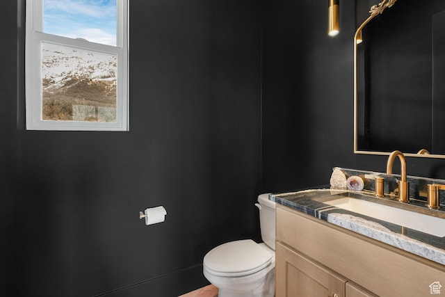 half bathroom featuring a wealth of natural light, toilet, and vanity