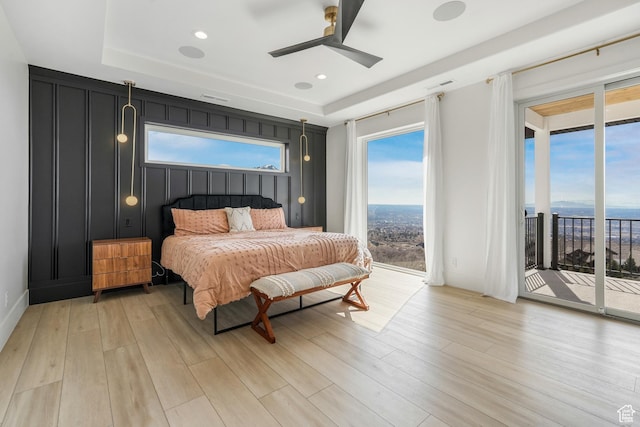 bedroom with multiple windows, light wood-style floors, and access to outside