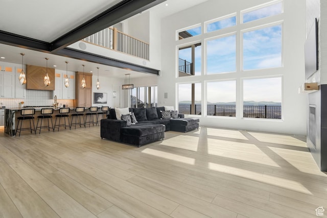 living area featuring light wood-style flooring and a towering ceiling