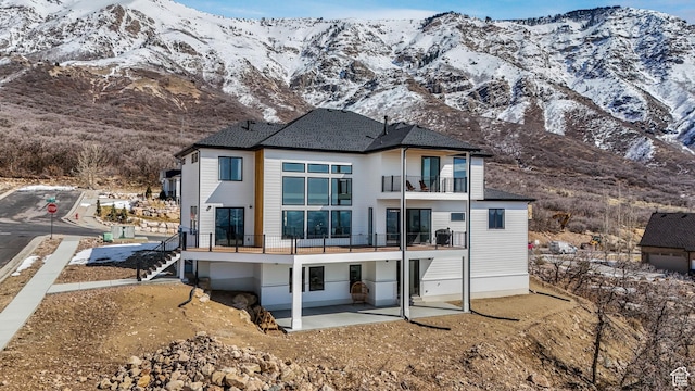 rear view of house featuring stairs, a balcony, a patio area, and a mountain view