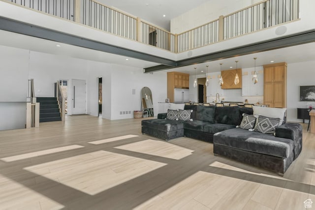 living room featuring light wood finished floors, stairway, arched walkways, and a towering ceiling