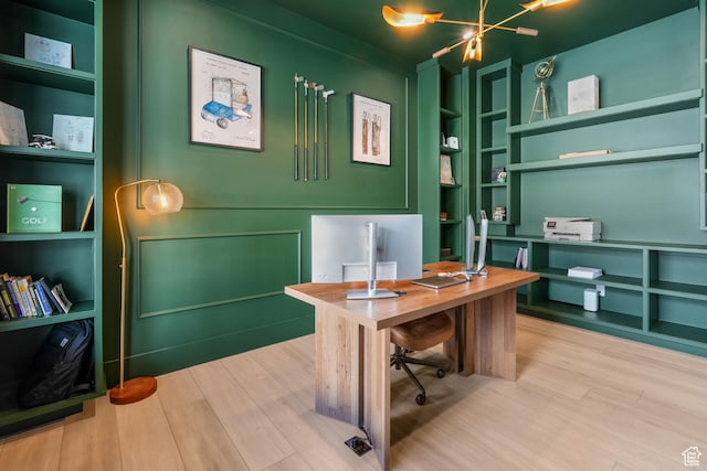 home office featuring an inviting chandelier, built in features, and wood finished floors