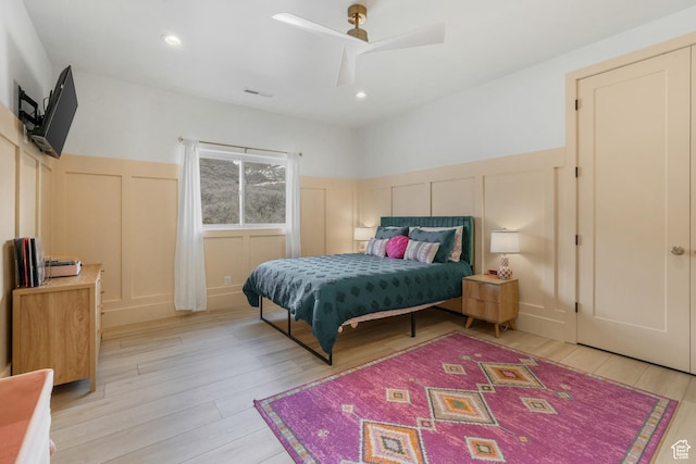 bedroom with visible vents, light wood-style flooring, and a decorative wall