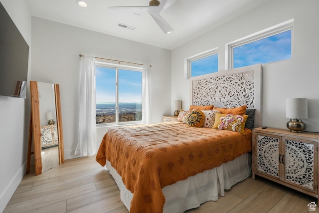 bedroom with a ceiling fan, visible vents, light wood finished floors, and baseboards