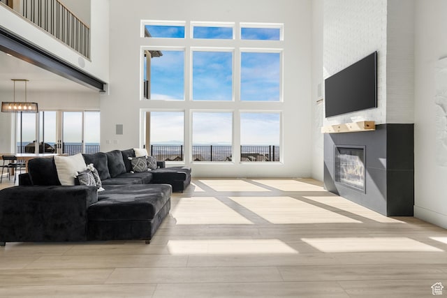 living area with wood finished floors, a towering ceiling, and a large fireplace